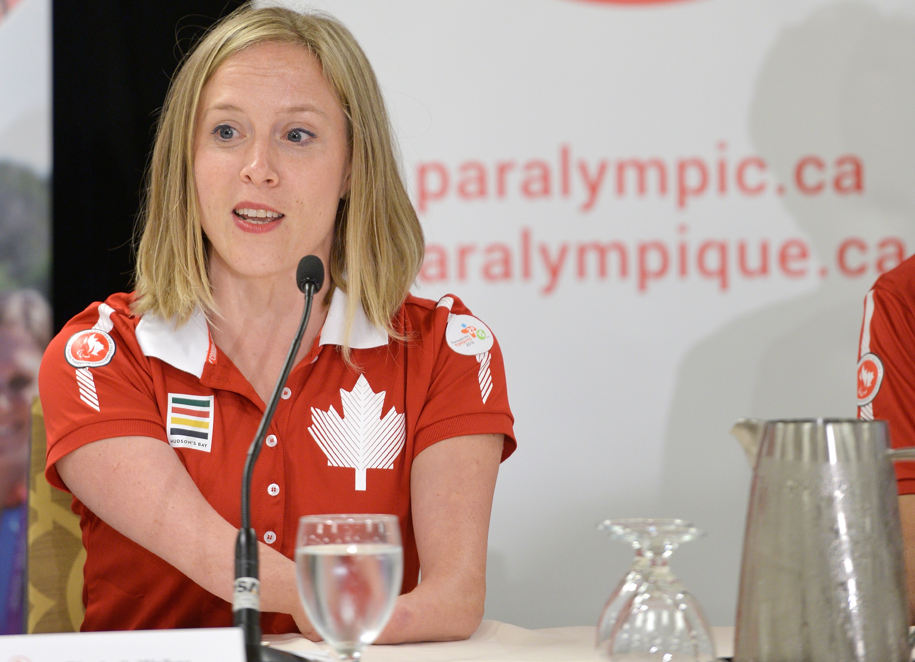 Chef de mission Elisabeth Walker-Young speaking in front of a microphone at a press conference for the Toronto 2015 Parapan Am Games