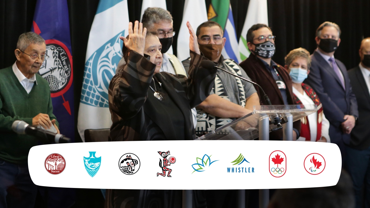 An image of Indigenous leaders at the podium with the eight logos of the BC2030 feasibility group members: the Lil̓wat7úl (Líl̓wat), xʷməθkʷəy̓əm (Musqueam), Sḵwx̱wú7mesh (Squamish) and səlilwətaɬ (Tsleil-Waututh) First Nations, the City of Vancouver, Resort Municipality of Whistler, Canadian Olympic Committee and Canadian Paralympic Committee