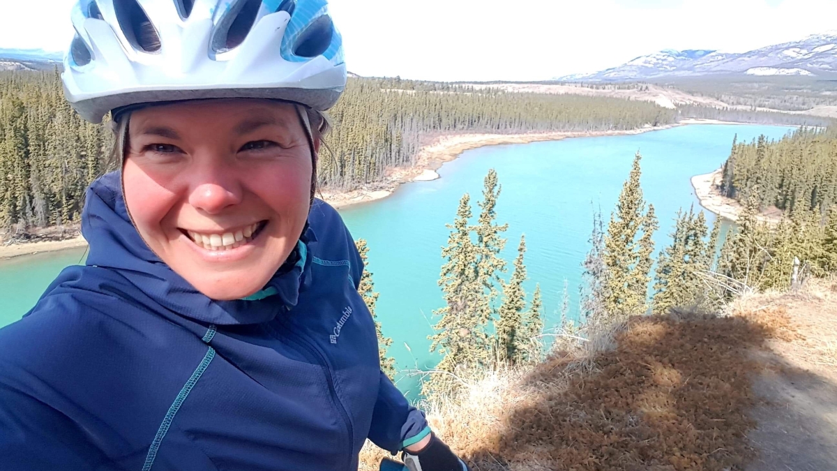 Stephanie Dixon on her bike in front of a lake in the Yukon. 