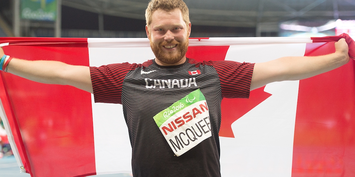 Alister McQueen holding a Canadian flag/ porte un drapeau canadienne