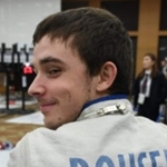Wheelchair fencer Ryan Rousell looking back at smiling at the camera as he watches the competition from the sidelines. 