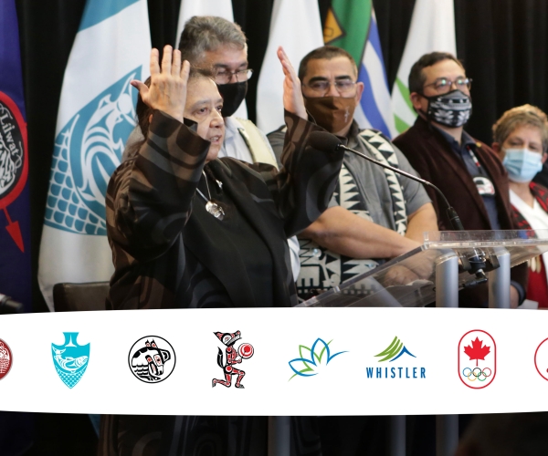 An image of Indigenous leaders at the podium with the eight logos of the BC2030 feasibility group members: the Lil̓wat7úl (Líl̓wat), xʷməθkʷəy̓əm (Musqueam), Sḵwx̱wú7mesh (Squamish) and səlilwətaɬ (Tsleil-Waututh) First Nations, the City of Vancouver, Resort Municipality of Whistler, Canadian Olympic Committee and Canadian Paralympic Committee