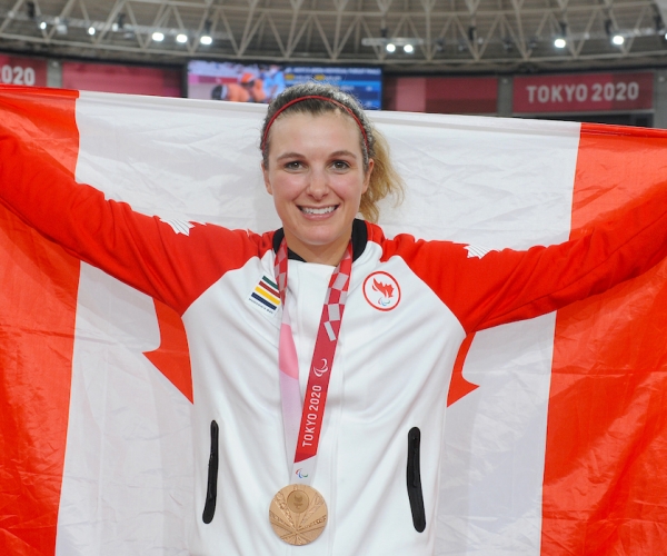 Keely Shaw holds the Canadian flag and wears her bronze medal