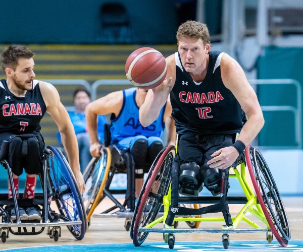 Pat Anderson in wheelchair basketball action, dribbling the ball