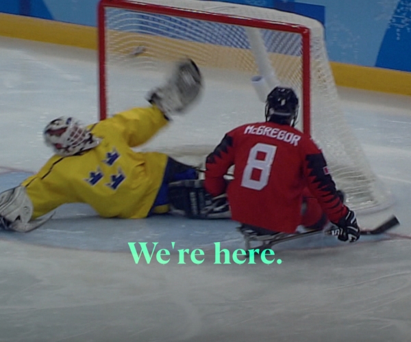 Tyler McGregor scoring a goal in Para ice hockey with the text 'We're Here' laid overtop