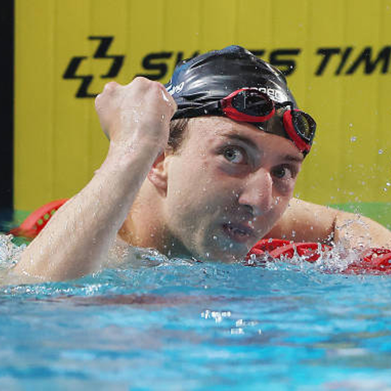 Canadian Para swimmer Alec Elliot pumps his fist in the air as he rests on a lane rope following a swimming race.