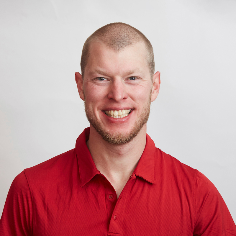 Portrait of Canadian Paralympian Mark Arendz smiling in front of a white background, wearing a red collared shirt.