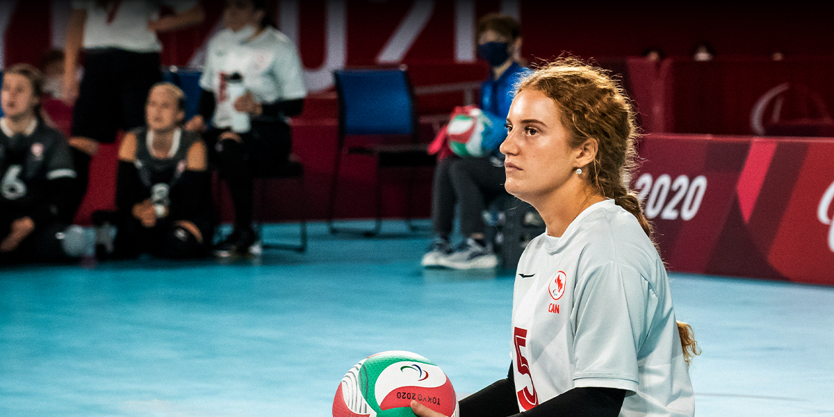 Canadian sitting volleyball player Payden Vair focuses intently while holding the ball during a match at the Tokyo 2020 Paralympic Games, wearing her Team Canada uniform.