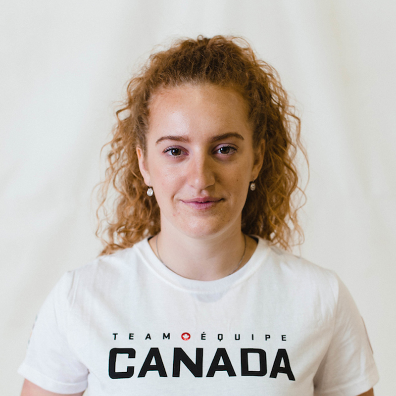 Portrait of Canadian sitting volleyball player Payden Vair, smiling softly while wearing a white Team Canada T-shirt against a neutral background.