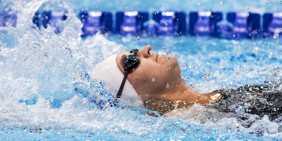 Canadian Para swimmer Nikita Ens during a backstroke race where she's taking a breath mid-stroke as her head is out of the water.