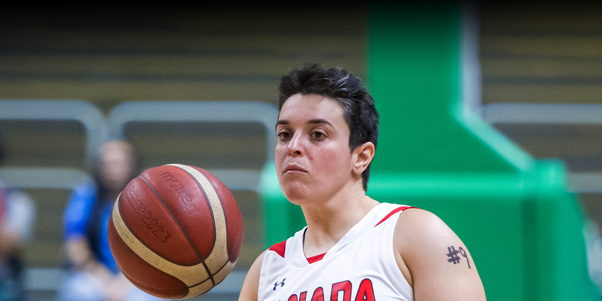 Canadian wheelchair basketball player Sofia Fassi-Fehri focuses on the ball during a game, wearing a white Team Canada jersey with the number 9 visible on her arm.