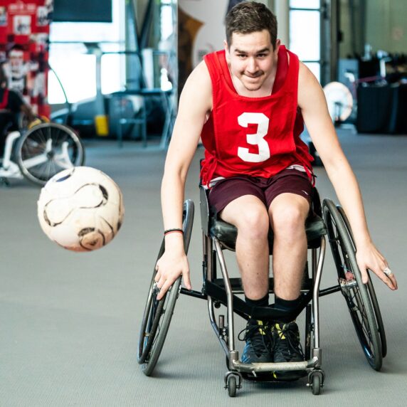 A Paralympian Search participant in a wheelchair races to catch a ball