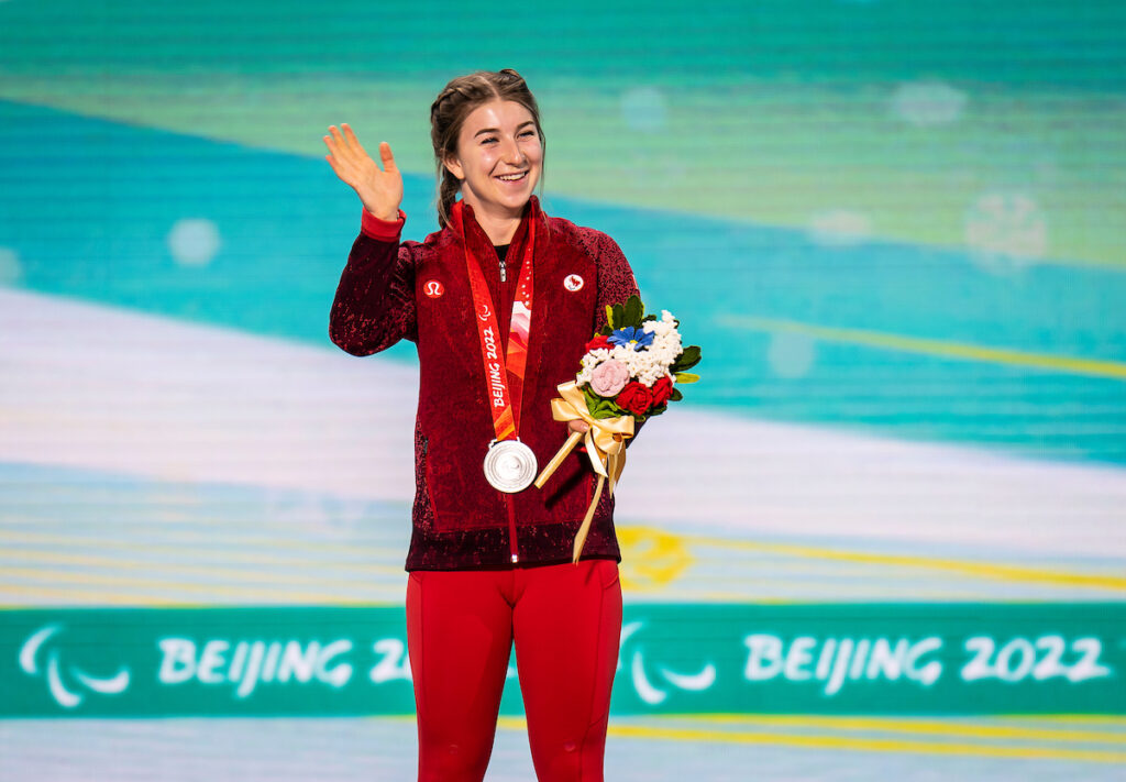 Mollie Jepsen smiling and waving with her silver medal in the giant slalom at Beijing 2022 Paralympic Winter Games