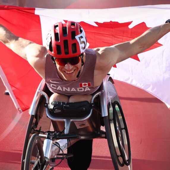 Anthony Bouchard in his racing chair waving the Canadian flag behind him