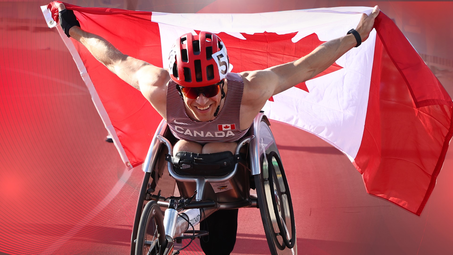 Anthony Bouchard in his racing chair waving the Canadian flag behind him