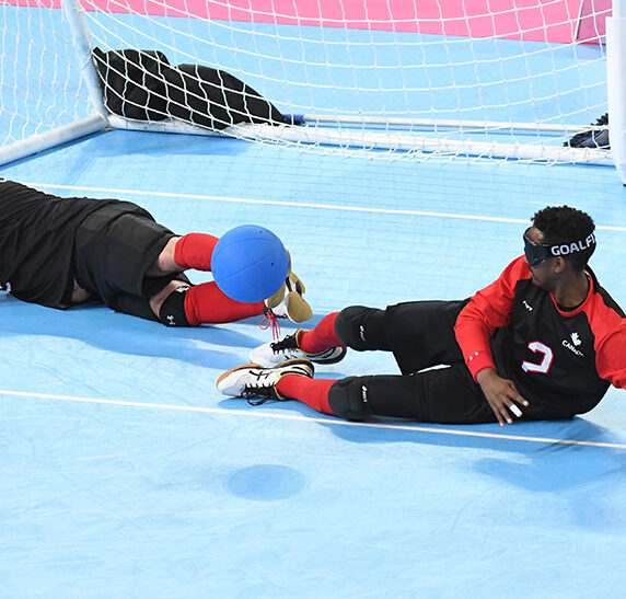 Goalball team stopping the ball from going into the net, players are laying down