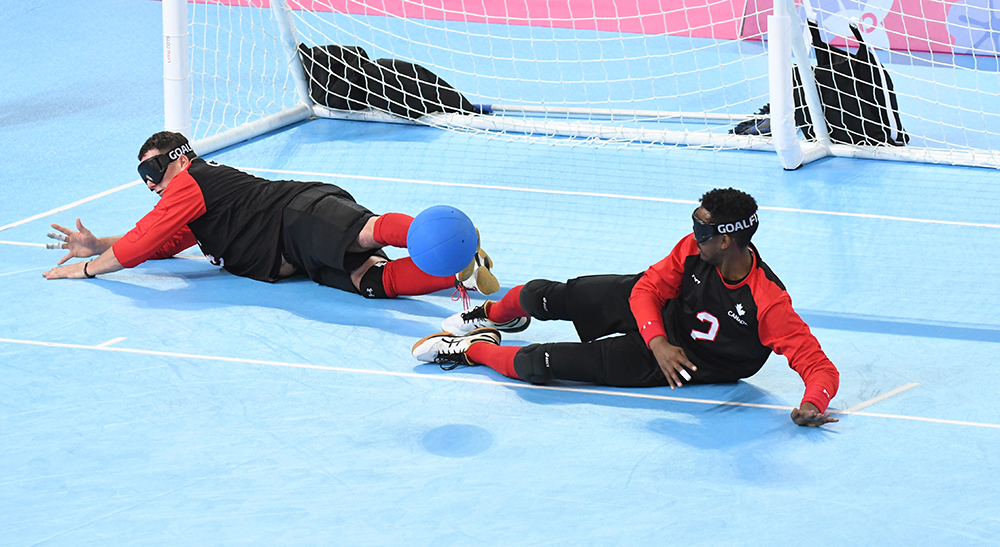 Goalball team stopping the ball from going into the net, players are laying down