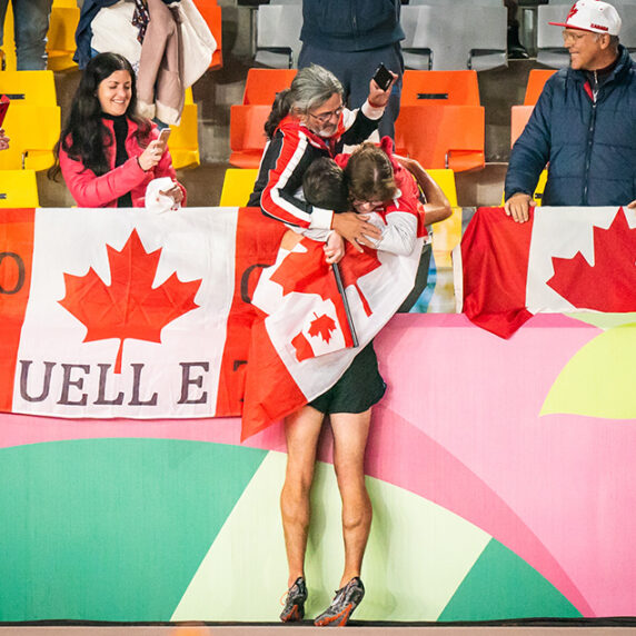 Guillaume Ouellet hugging his family with flags all around him
