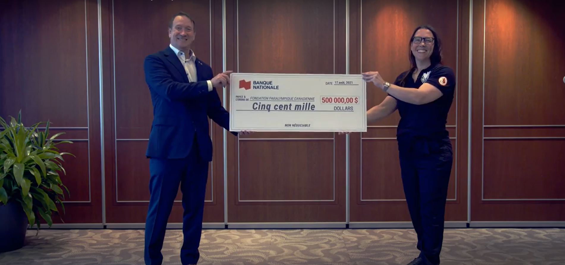 Louis Vachon, president and CEO of National Bank, and Paralympian Karolina Wisniewska hold up a $500,000 cheque in support of the Paralympic Foundation of Canada.