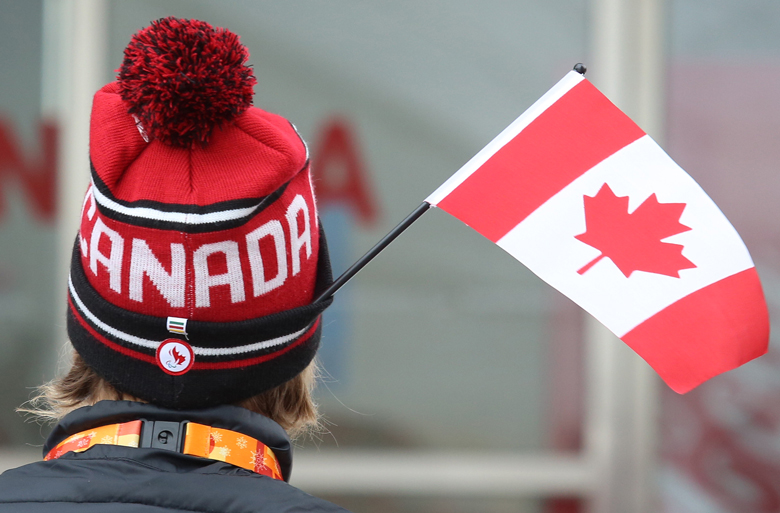 The back of a person's head wearing a Team Canada toque with a Canadian flag sticking out of the hat