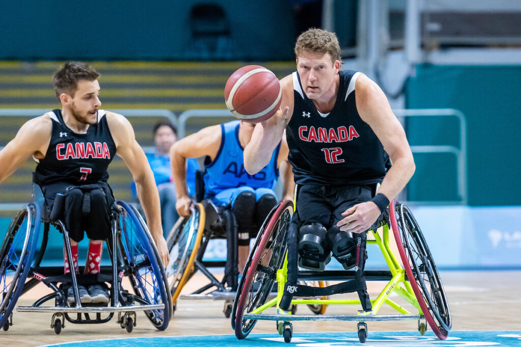 Pat Anderson in wheelchair basketball action, dribbling the ball