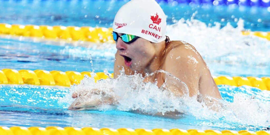 Canadian Para swimmer Nicholas Bennett competing in a breaststroke swimming race as he emerges from the water taking a breath before going into his stroke.