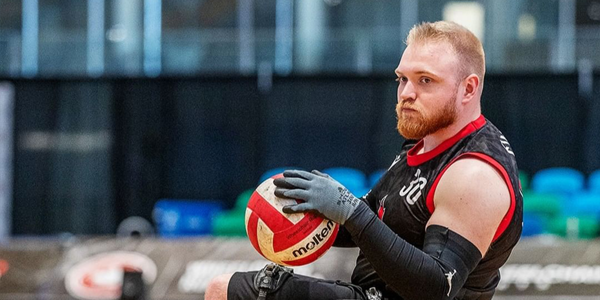 Canadian Wheelchair rugby player Joel Ewert is holding the ball during a match.