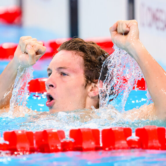 Nicholas Bennett raises his arms in the pool after winning gold.