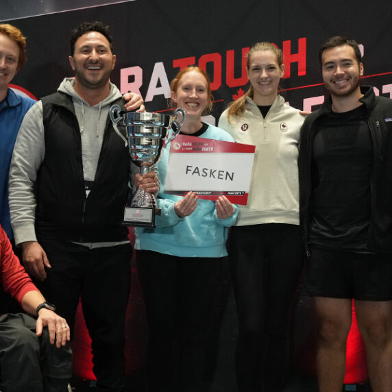 Team members from Fasken, winners of the Vancouver ParaTough Cup, stand together smiling and holding their trophy. Paralympian Josh Dueck is seated in front in a wheelchair, wearing a red shirt. The group poses in front of a ParaTough backdrop.