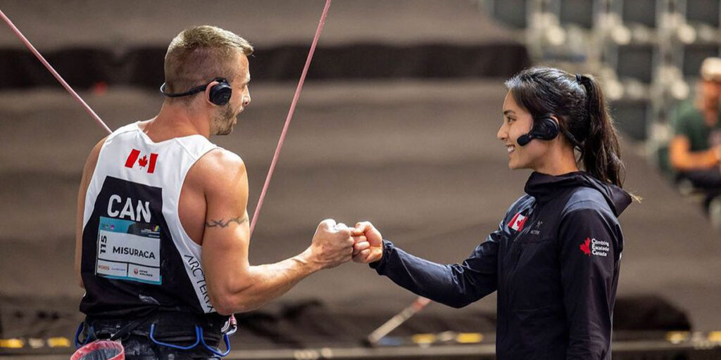 Blind Canadian Para climber Chaz Misuraca fist bumps with his guide Alannah Yip before he begins climbing up the wall.