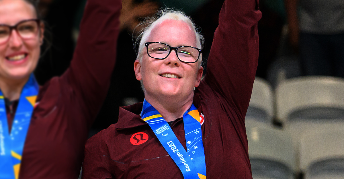 Canadian Goalball player Whitney Bogart celebrates on the podium at the Santiago 2023 Parapan American Games after receiving her gold medal alongside her teammates.