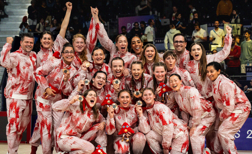 The Canadian women’s sitting volleyball team celebrates winning bronze at the Paris 2024 Paralympics. The team poses together in their red and white patterned uniforms, smiling and proudly holding their bronze medals and Paralympic mascots. Their joy and unity radiate as they commemorate this remarkable achievement on the world stage.
