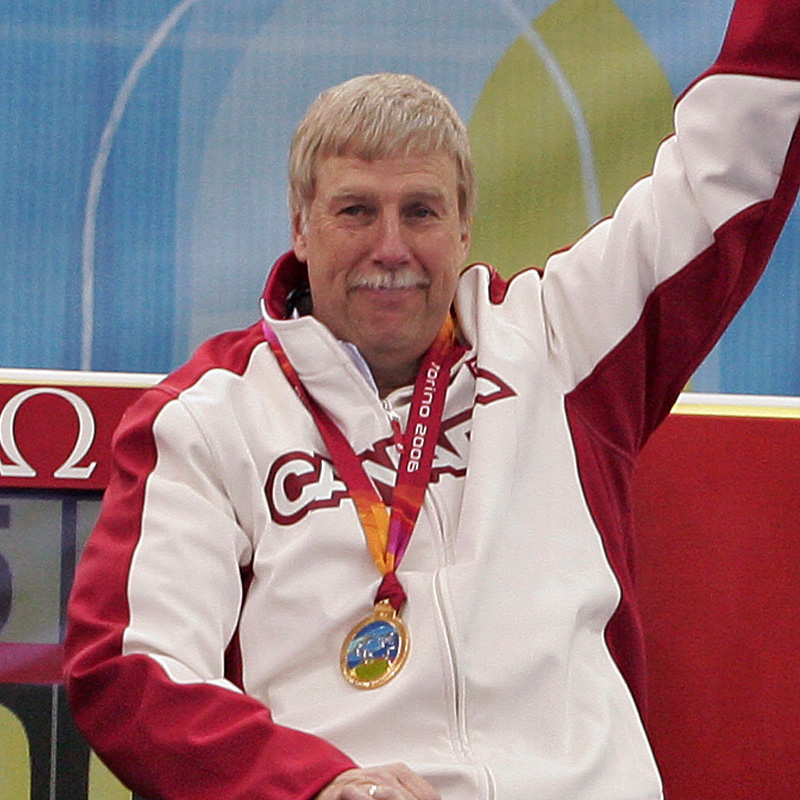 Canadian wheelchair curler Gary Cormack wearing a gold medal and Team Canada jacket, raising his arm in celebration.