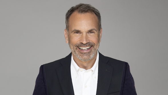 A professional headshot of Robert Cassius de Linval, a smiling man with short grey hair and a beard, wearing a dark suit jacket and a white shirt, standing against a plain grey background.