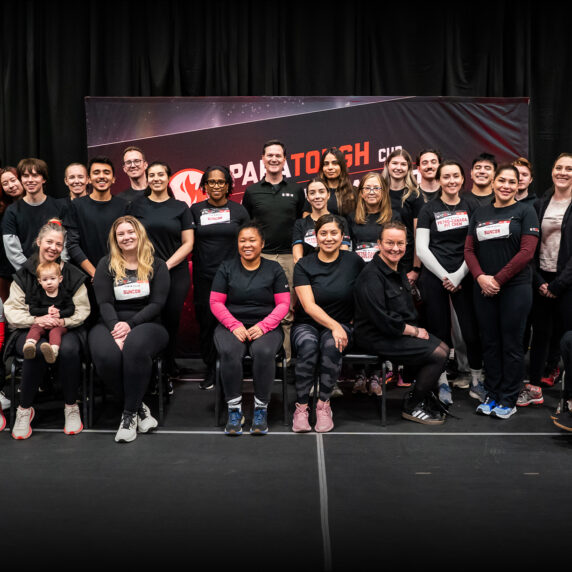 A group photo of Petro-Canada staff and Canadian Paralympians at the ParaTough Cup Calgary event. Participants are gathered in front of a black and red event backdrop with the ParaTough Cup logo, smiling and posing together. Some individuals are seated, including athletes in wheelchairs, while others stand behind them. The group showcases diversity in age, background, and roles, united in support of Para sport.