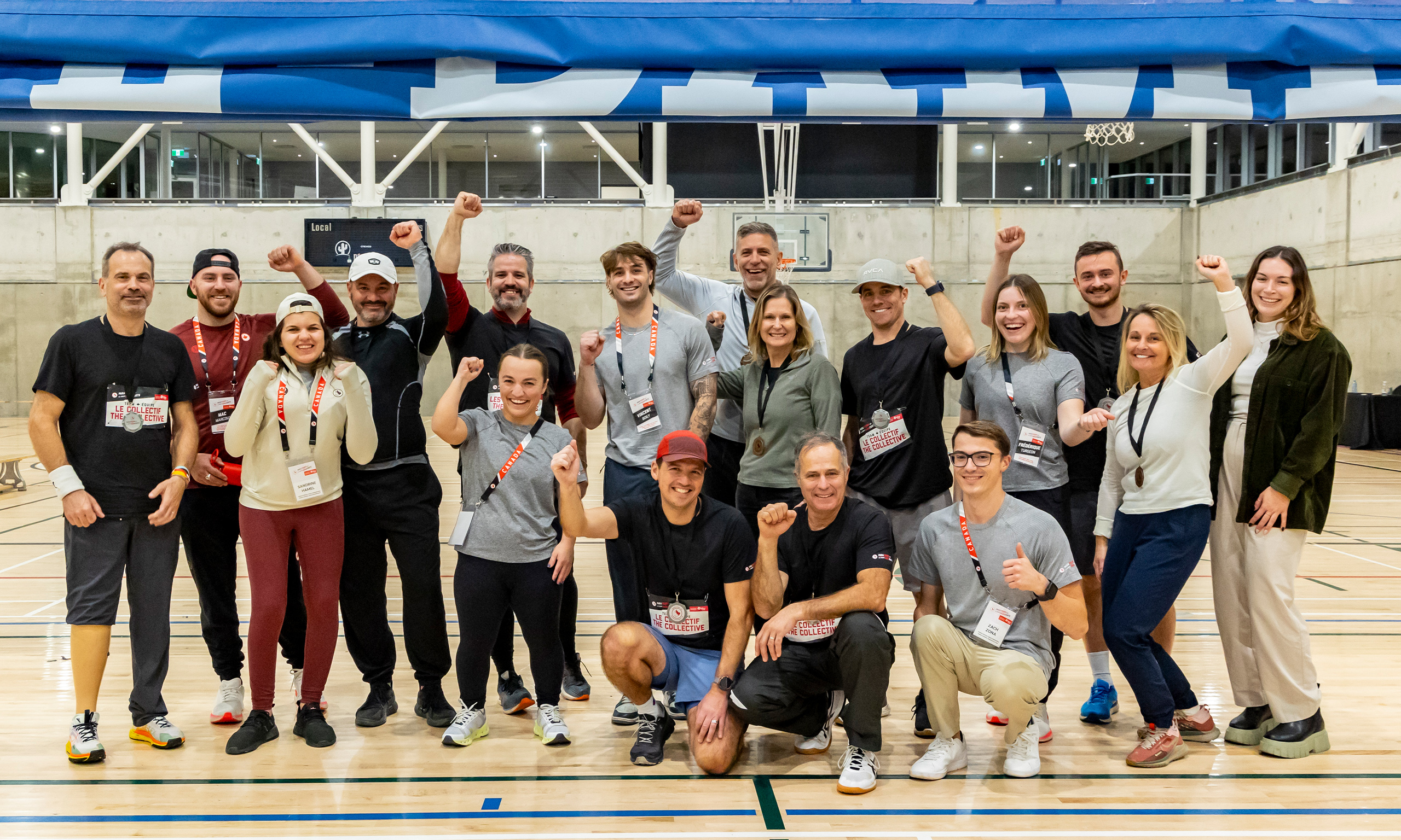 A group of smiling participants and volunteers pose together in a gymnasium with raised fists after taking part in the ParaTough Cup event in Montreal, celebrating their support for Para sport in Canada.