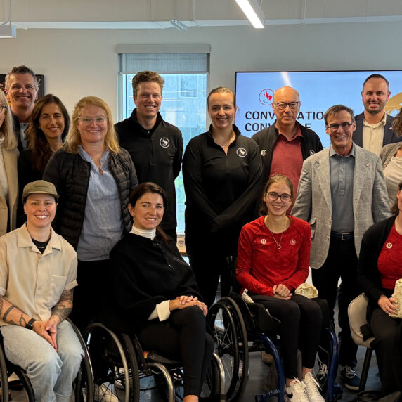 Members of the Canadian Paralympic Committee Board of Directors pose together indoors for a group photo during their board retreat. The group includes Para athletes, executives, and staff, smiling and gathered together.