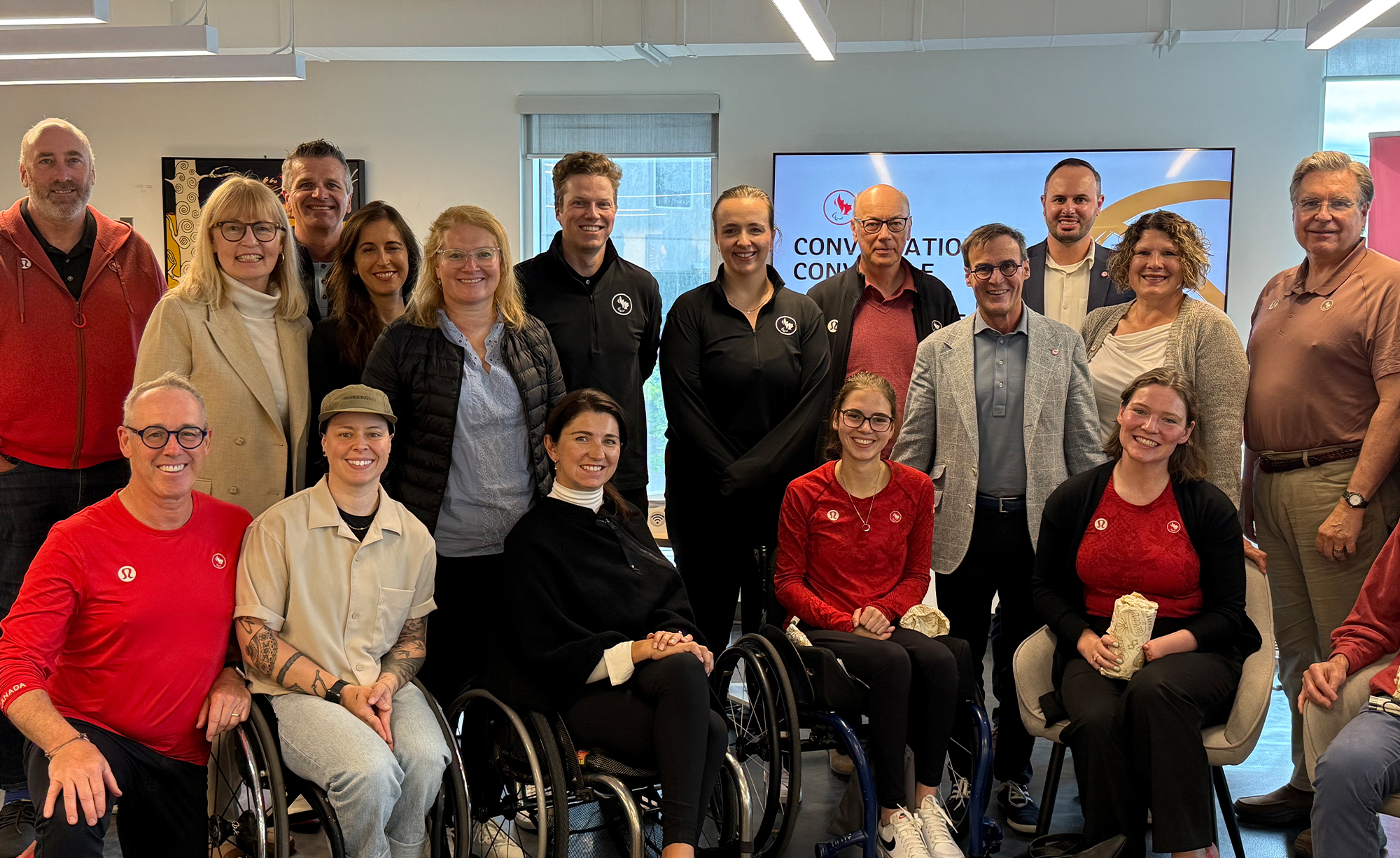 Members of the Canadian Paralympic Committee Board of Directors pose together indoors for a group photo during their board retreat. The group includes Para athletes, executives, and staff, smiling and gathered together.
