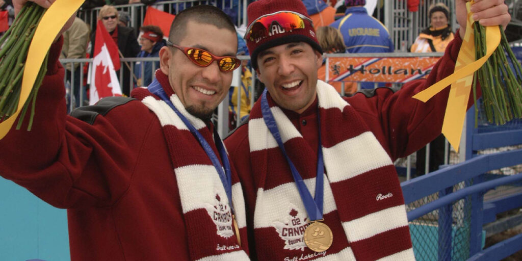 Canadian Paralympians Brian and Robin McKeever celebrate on the podium with their medals and flowers at the Salt Lake City 2002 Paralympic Winter Games.
