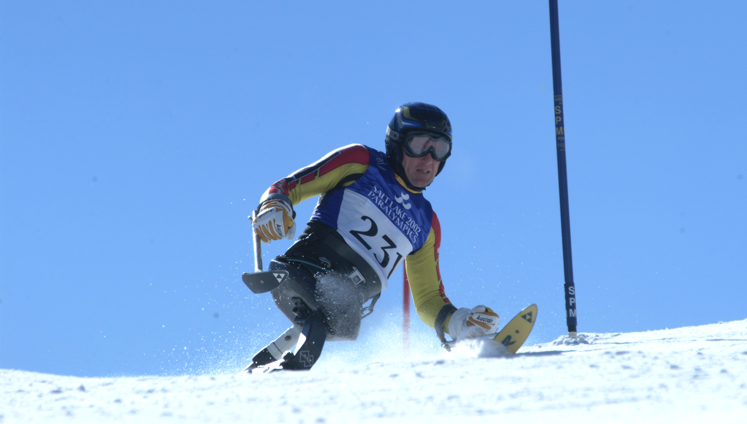 Canadian Para alpine skier Daniel Wesley races downhill in a sit-ski during the Salt Lake City 2002 Paralympic Winter Games, wearing bib number 231 and a blue race vest.