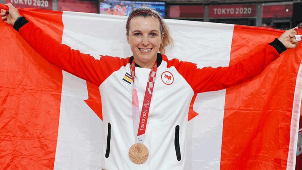 Keely poses with Canada flag behind her and a medal around her neck