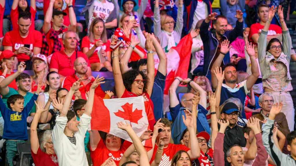 Stands at a para sporting event filled with canadian fans raising their hand and holding up Canadian flags